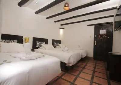a room with three beds with white sheets at Hatun Inti Classic in Machu Picchu