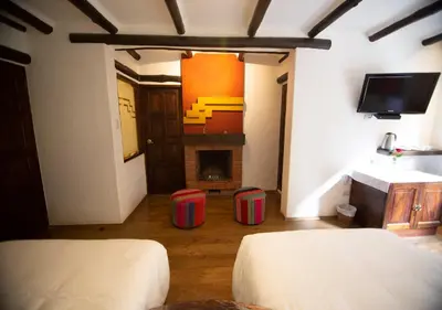 a room with two beds and a fireplace at Hatun Inti Boutique in Machu Picchu