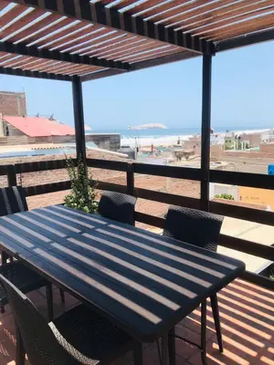 a blue table and chairs on a deck with the beach at Hospedaje Casa de Playa Arica in Lurín