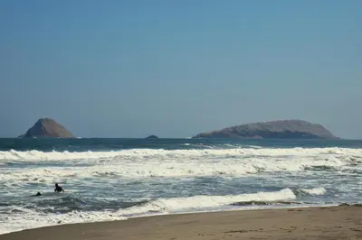 a couple of people in the water at the beach at Hospedaje Casa de Playa Arica in Lurín