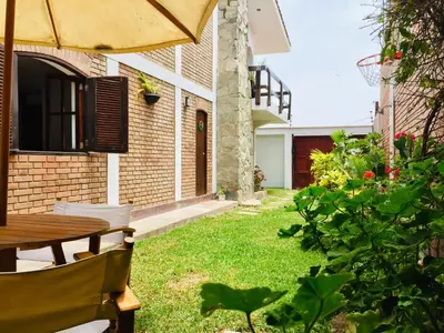 a garden with a wooden table and an umbrella at Hospedaje Casa de Playa Arica in Lurín