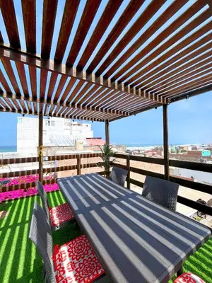 a wooden pergola with a table and chairs on a balcony at Hospedaje Casa de Playa Arica in Lurín