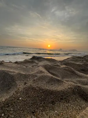 a sunset over the ocean with a sandy beach at Hospedaje Casa de Playa Arica in Lurín