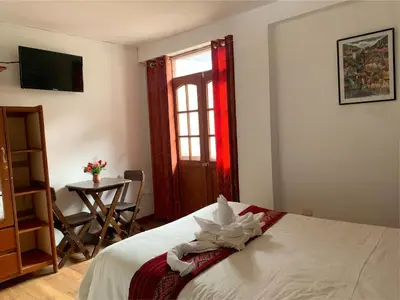 a bedroom with a bed and a table and a window at Inka Khawarina Tambo Lodge in Ollantaytambo