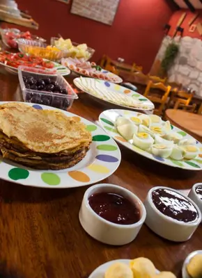 a wooden table topped with plates of pancakes and sauce at Hostal Teatro Inka in Cusco
