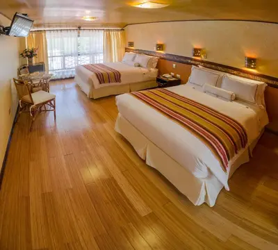 a hotel room with two beds and a table at Hotel Taypikala Machupicchu in Machu Picchu