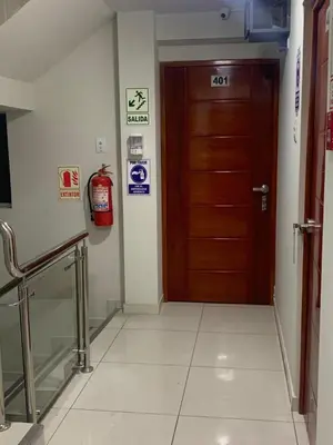 a hallway with a brown door and a fire extinguisher at A-Hope Suite Hotel in Huancayo