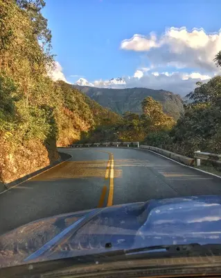 a car driving down a road with mountains in the background at Eco Quechua Lodge in Santa Teresa