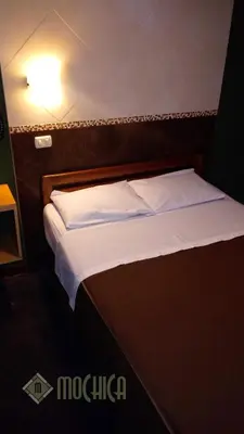 a bed with white sheets and pillows in a room at Hostal Residencial Mochica in Lima