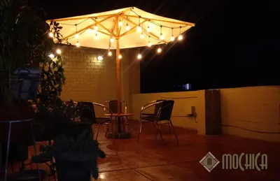an umbrella with lights on a patio at night at Hostal Residencial Mochica in Lima