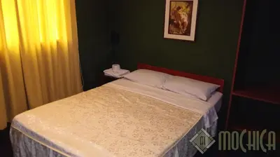 a small bed in a bedroom with a green wall at Hostal Residencial Mochica in Lima