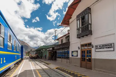 a train is parked next to a train station at El Albergue Ollantaytambo in Ollantaytambo