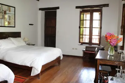 a bedroom with a bed and a table with a vase of flowers at El Albergue Ollantaytambo in Ollantaytambo