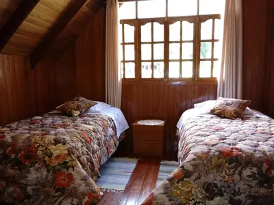 a bedroom with two beds and a window at La Cabaña de Noa in Oxapampa