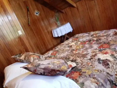 a bed with a floral bedspread and pillows at La Cabaña de Noa in Oxapampa