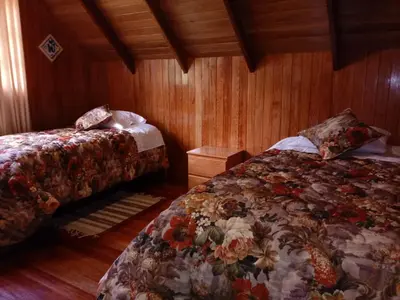 a bedroom with two beds and wooden walls at La Cabaña de Noa in Oxapampa