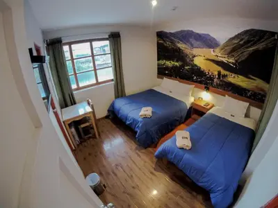 a room with two beds and a painting on the wall at Net House Cusco in Cusco