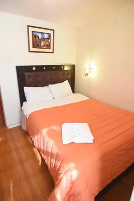 a bedroom with a large orange bed with two towels on it at Tambo Cusco Inn in Cusco