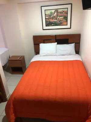a bedroom with a bed with an orange blanket at Tambo Cusco Inn in Cusco