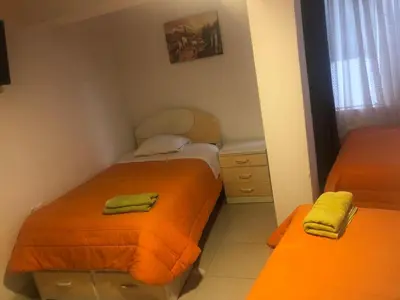 two beds in a small room with orange sheets at Tambo Cusco Inn in Cusco