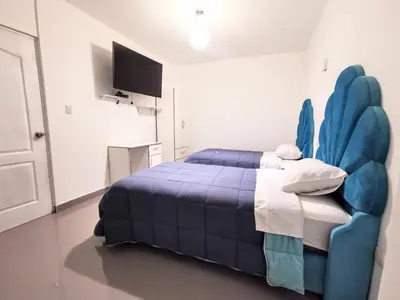 a bedroom with a blue bed and a tv at AQUAMARINE PARACAS Beach Hostal in Paracas
