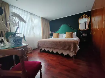 a bedroom with a bed with a green headboard and a mirror at Ana Frank Boutique Hotel in Lima