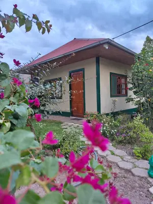 a small house with pink flowers in front of it at Hospedaje Cattleya in Oxapampa