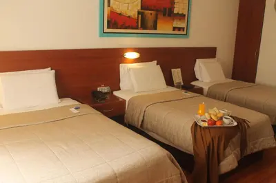 a hotel room with two beds and a tray of fruit at Hotel Vila Santa in Lima