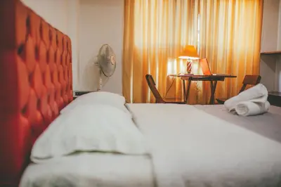 a bedroom with a bed and a table with a fan at Hotel Excalibur in Lima