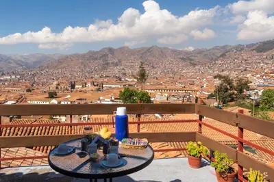 a table on a balcony with a view of a city at Samay Wasi Hostel in Cusco