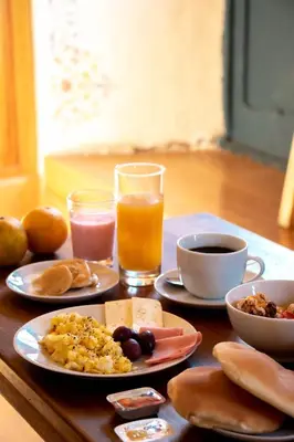 a table with plates of breakfast foods and drinks at Nao Victoria Hostel in Cusco