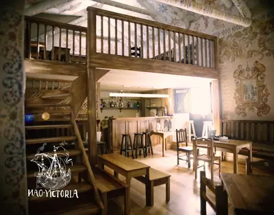 a room with tables and chairs and a staircase at Nao Victoria Hostel in Cusco