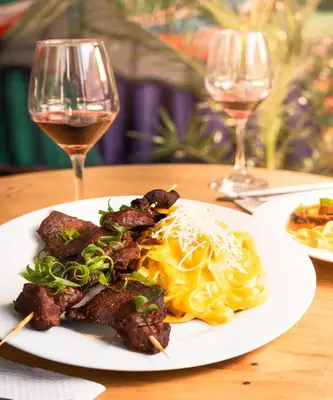 a plate of food on a table with two glasses of wine at Hotel Turin in Tarma
