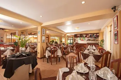 a restaurant with tables and chairs in a room at Hotel Mabey Urubamba in Urubamba