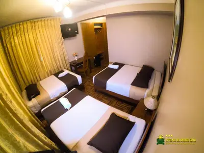 a hotel room with two beds and a table at Hotel Sol del Oriente Cusco in Cusco