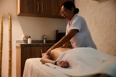 a woman sitting on a bed getting a massage at Casa Andina Select Miraflores in Lima