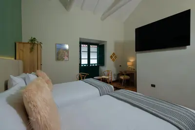 a bedroom with a large white bed with a flat screen tv at Hotel Hacienda Sonqori Centro Histórico in Cusco