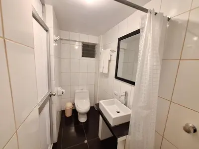 a white bathroom with a toilet and a sink at Mapi Garden's Machupicchu in Machu Picchu