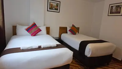 two beds in a hotel room with white sheets at Mapi Garden's Machupicchu in Machu Picchu