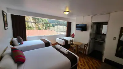 a hotel room with two beds and a window at Mapi Garden's Machupicchu in Machu Picchu