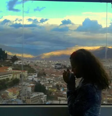 a woman brushing her teeth in front of a window at Feliz Vista Casa-Hospedaje in Cusco