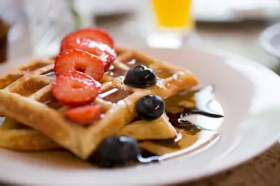 a plate of waffles with strawberries and berries on it at Belma Boutique Bed and Breakfast in Lima