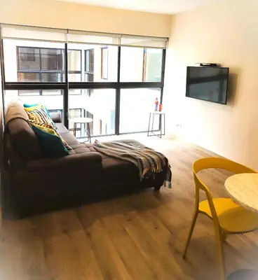 a living room with a couch and a large window at LA POSADA DE GUILLE LUXURY 1 HABITACION - Surco in Lima