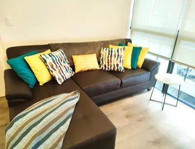 a brown couch with colorful pillows on it in a living room at LA POSADA DE GUILLE LUXURY 1 HABITACION - Surco in Lima