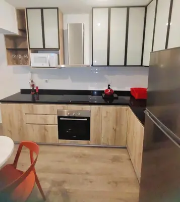 a kitchen with wooden cabinets and a black counter top at LA POSADA DE GUILLE LUXURY 1 HABITACION - Surco in Lima