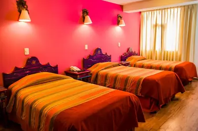 three beds in a room with pink walls at Hotel Warari in Cusco