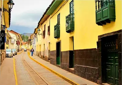 a yellow building with green doors on a street at Cuzco Central Hostel in Cusco