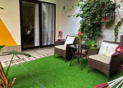 a patio with two chairs and a table with green grass at Casa Samaykuy in Ayacucho