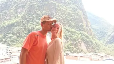 a man and a woman standing in front of a mountain at Picos House MachuPicchu in Machu Picchu