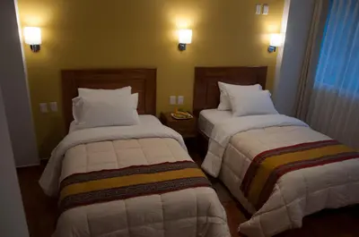 a hotel room with two beds with white sheets at Picos House MachuPicchu in Machu Picchu